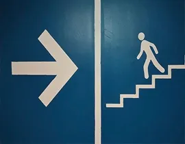 Señal con una flecha y un señor bajando una escalera