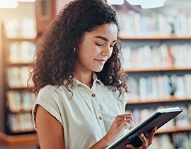 Chica en una biblioteca consultando una tablet