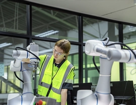 Operaria con un robot industrial y ropa de trabajo