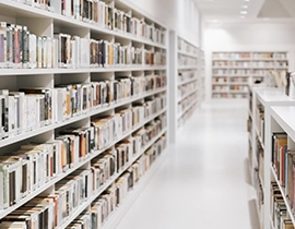Estanterías llenas de libros ordenados y clasificados en una biblioteca con pasillo vacío