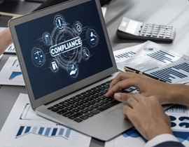 Persona utilizando un portátil cuya pantalla tiene una imagen con la palabra "Compliance" e iconos relativos a esta temática.