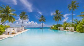 Piscina con palmeras y el mar de fondo
