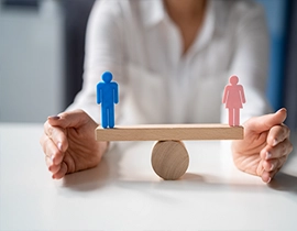 Una balanza de madera en equilibrio con una figura de hombre en un lado y en el otro la figura de una mujer