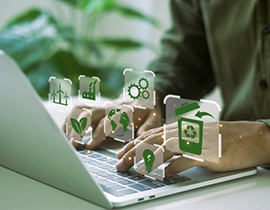 Persona trabajando con un portátil con iconos medioambientales sobre sus manos al teclear